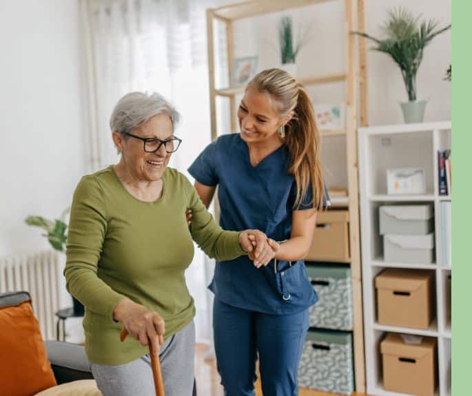 Smiling nurse assisting senior woman with a cane during home care support provided by Advanced Nursing & Home Care