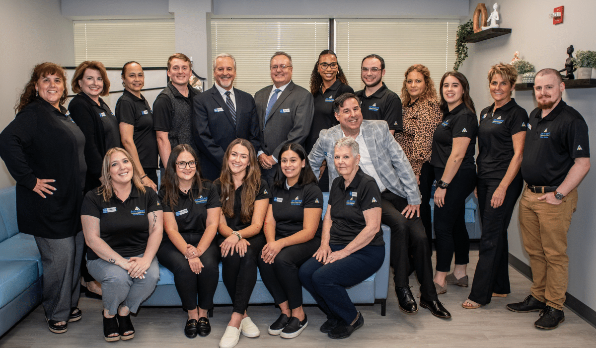Team members of Advanced Nursing & Home Care smiling together in an office setting, representing compassionate and professional home care services.