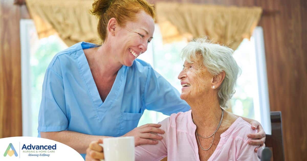 A caregiver and client smile while the caregiver hugs and helps the client, representing professional caregiving.