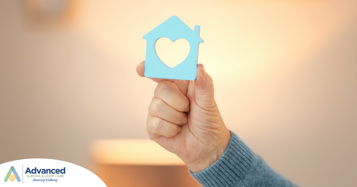 A hand holds up a cutout of a home with a heart in it, representing the home care industry.
