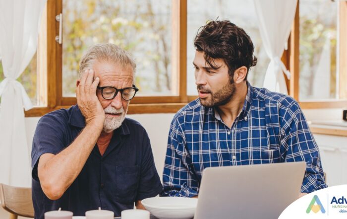A man looks at a computer with his father who is confused, representing one of the early signs of dementia.