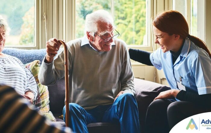 A caregiver is smiling and supporting an elderly man with a cane while another senior woman looks on, showing trust and compassionate home care.