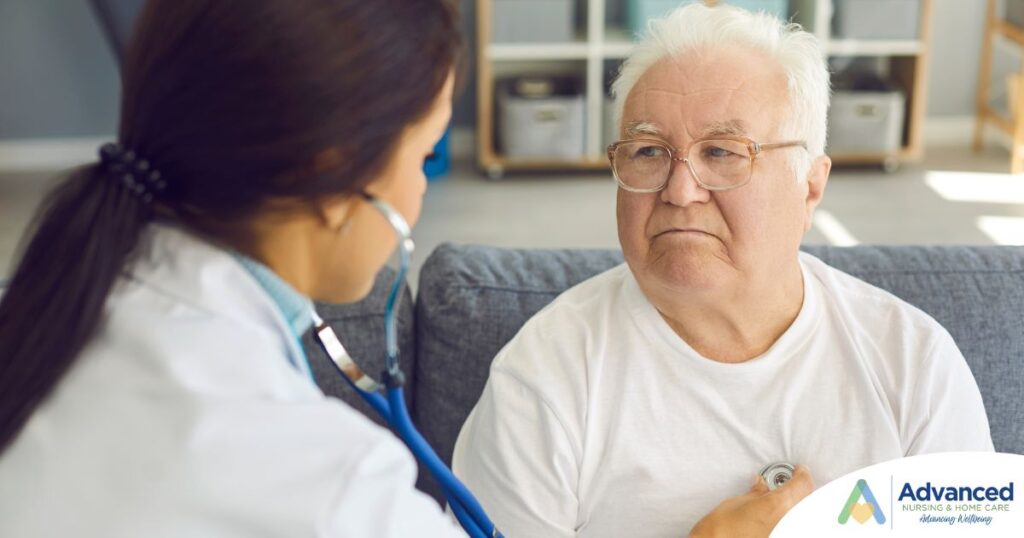 A nurse uses a stethoscope to check the heart of an elderly man at home, representing the professional medical support offered by Advanced Nursing & Home Care.