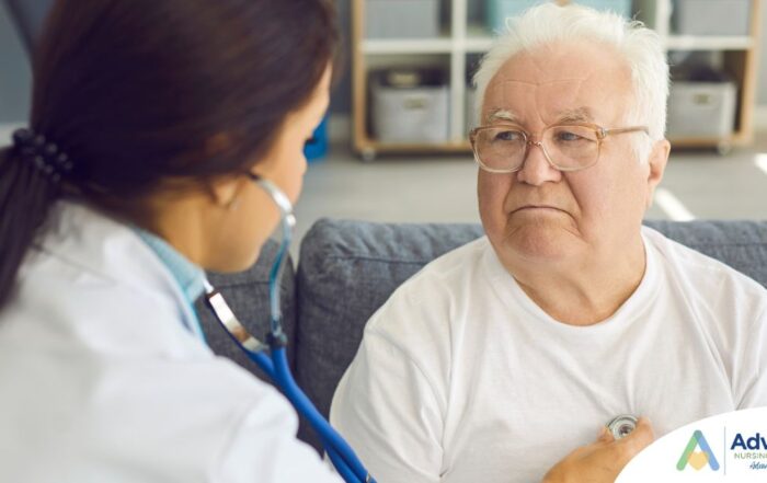 A nurse uses a stethoscope to check the heart of an elderly man at home, representing the professional medical support offered by Advanced Nursing & Home Care.