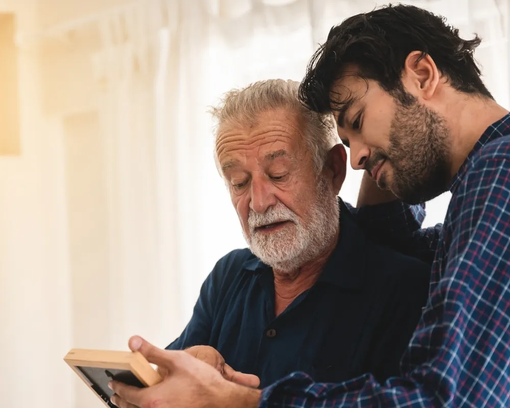 Adult son with senior father looking at photo