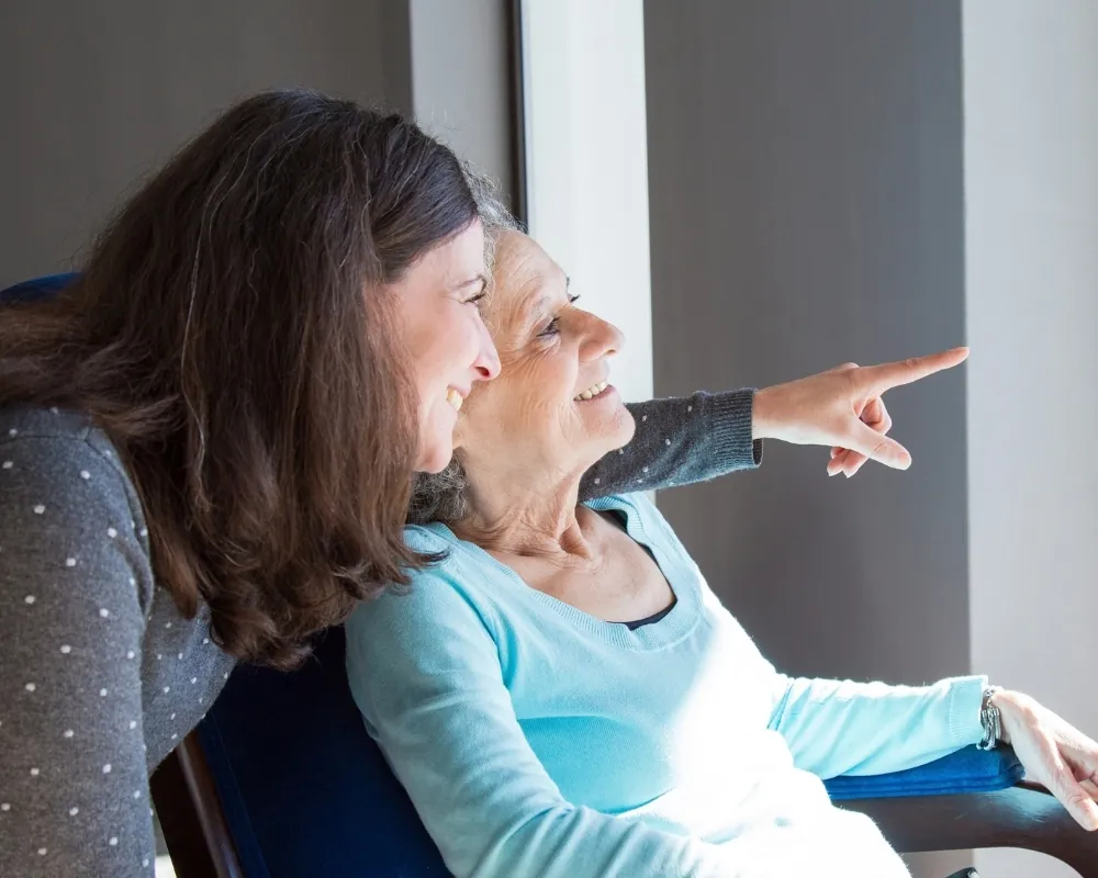 Caregiver and senior woman looking out window