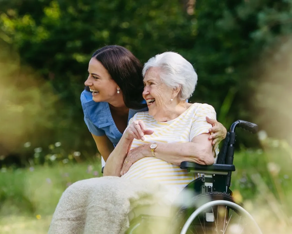 Caregiver and senior woman in wheelchair outdoors
