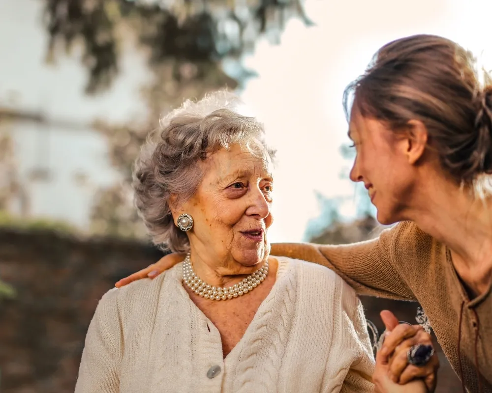 Caregiver arm around senior woman outside