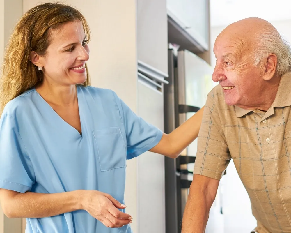 Caregiver assisting senior man in kitchen