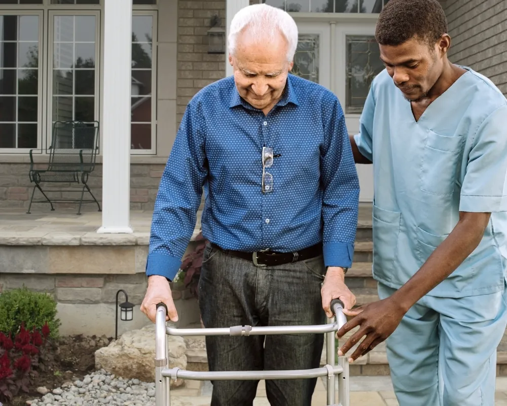Caregiver assisting senior man with walker outdoors
