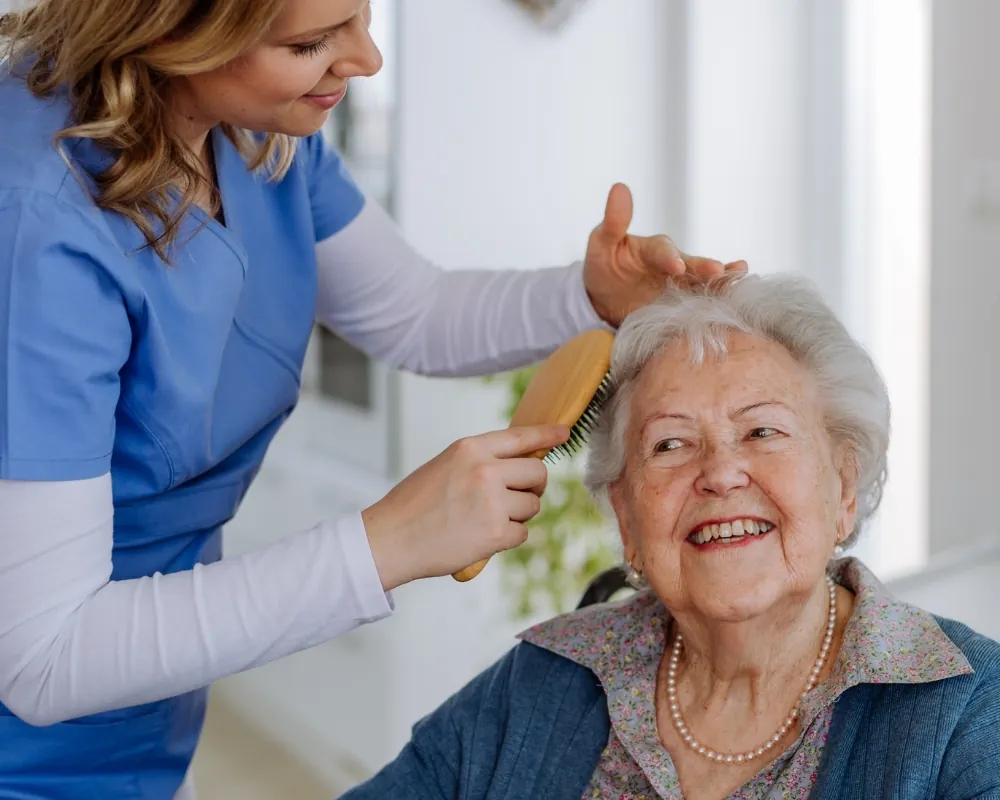 Caregiver brushing senior woman's hair