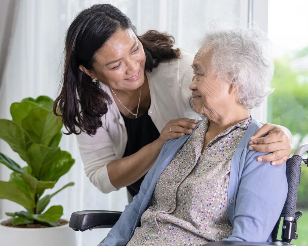 Caregiver comforting elderly woman in wheelchair