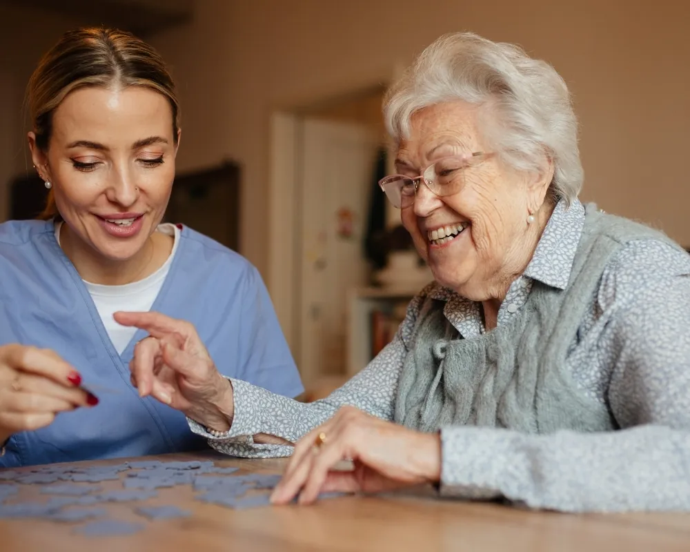 Caregiver doing jigsaw puzzle with senior woman