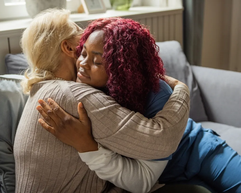 Caregiver embracing senior woman at home