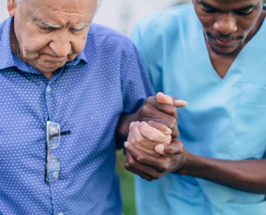 Caregiver holding hands with senior for mobility support
