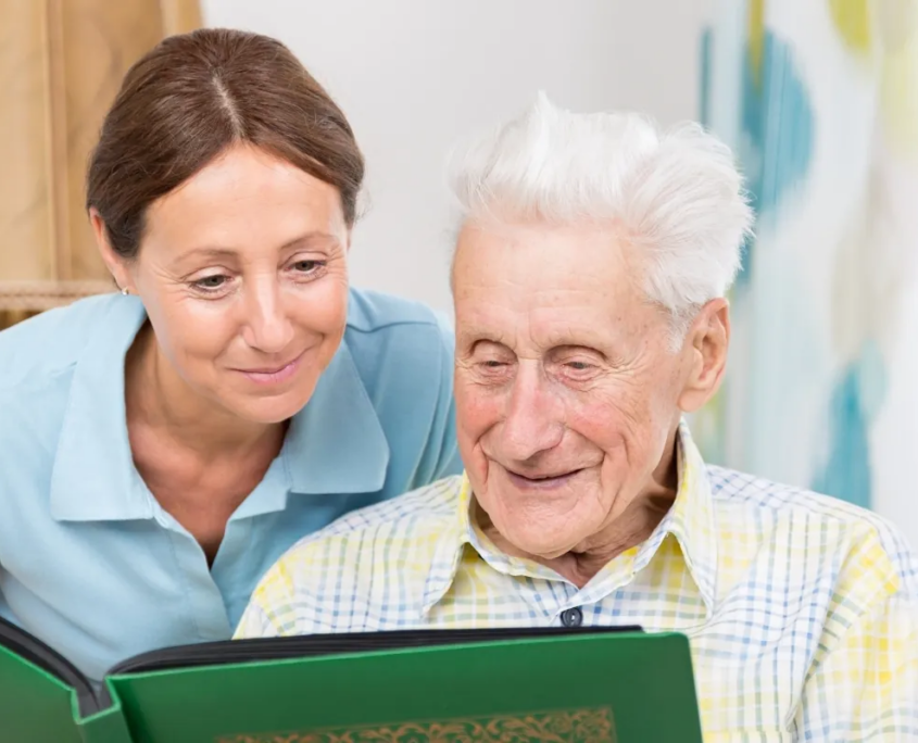 Caregiver looking at photo album with elderly man