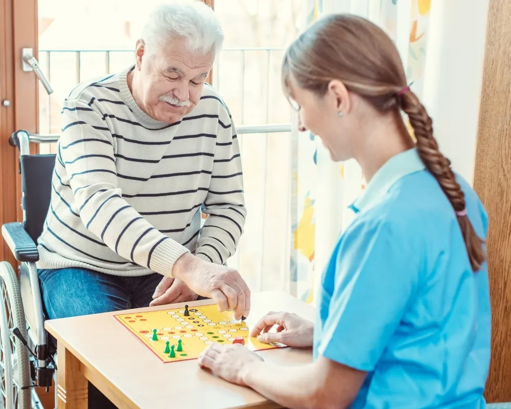 Caregiver playing board game with senior in wheelchair