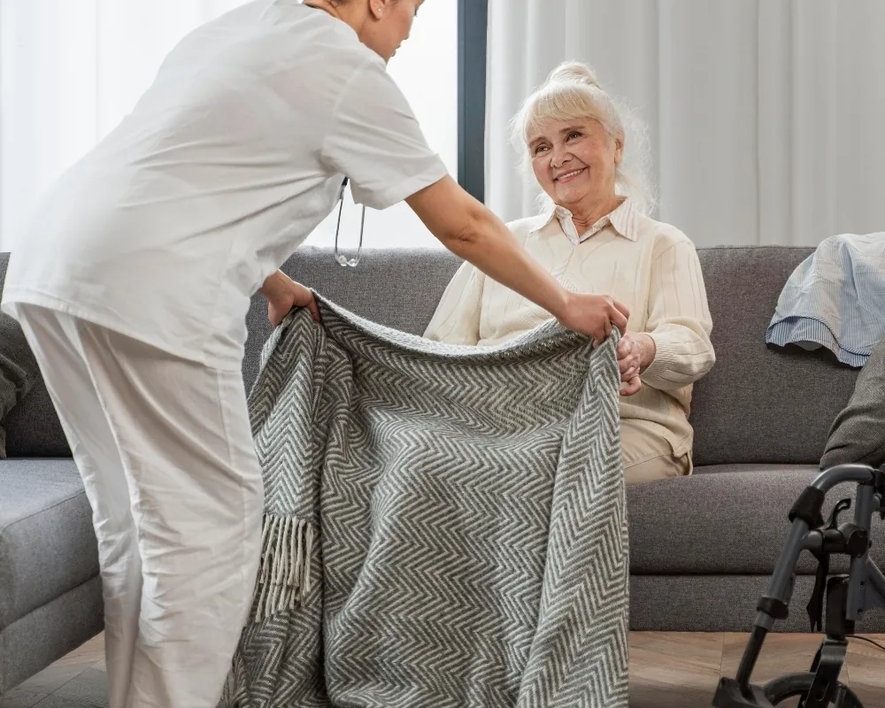 Caregiver tucking blanket for senior woman