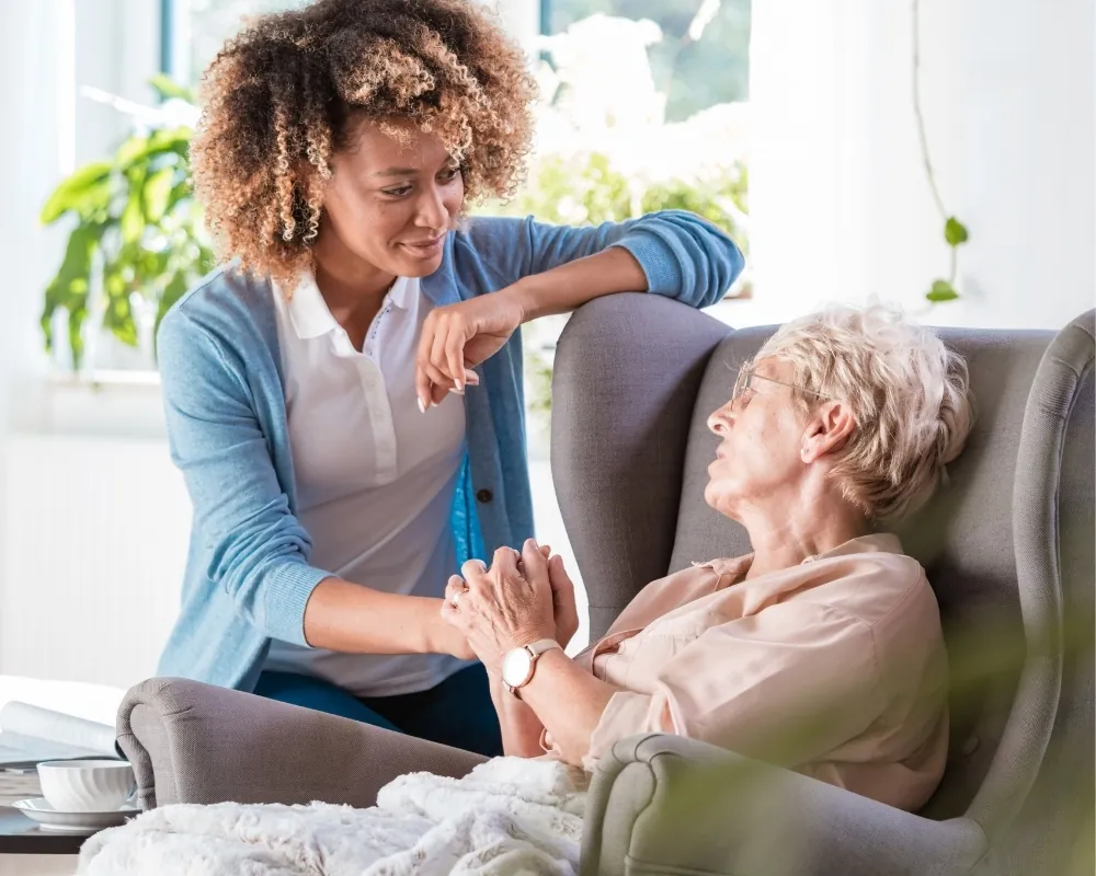 Caregiver visiting senior woman in armchair