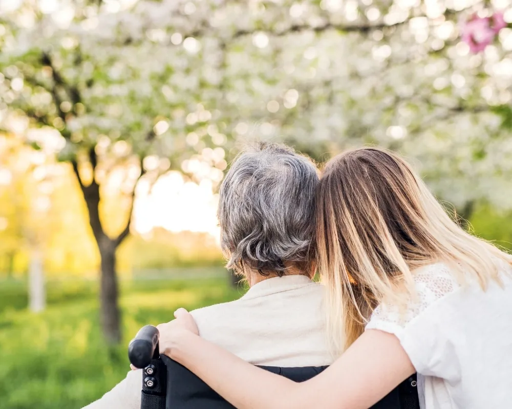 Caregiver with senior under blossoming trees