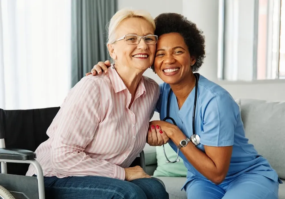 Nurse and senior woman smiling together on sofa