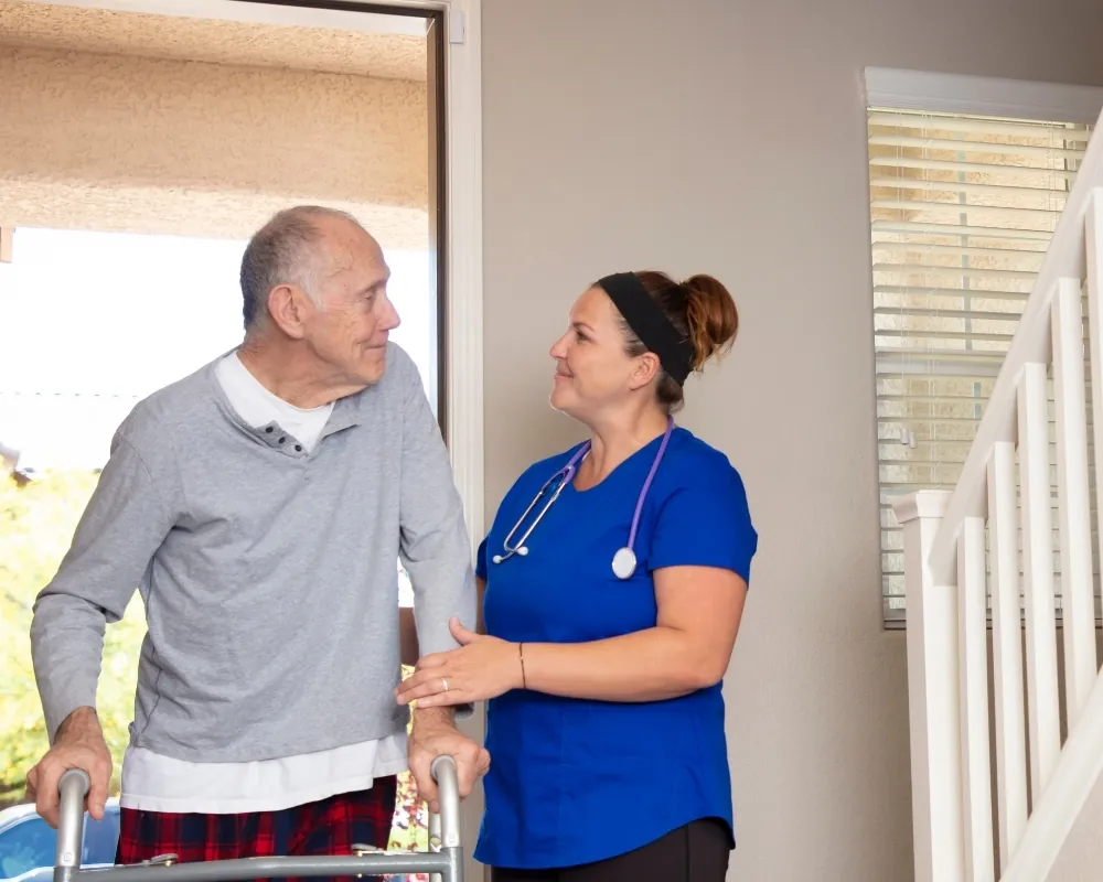 Nurse assisting senior man with walker at home