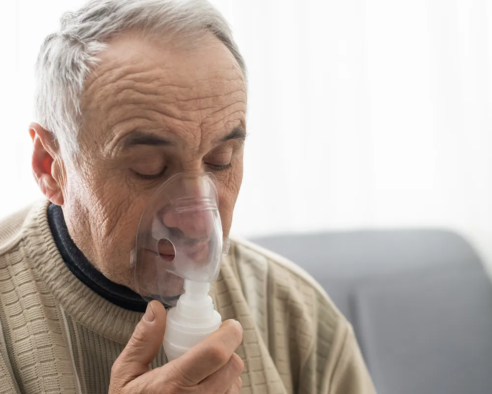 Senior man using nebulizer at home
