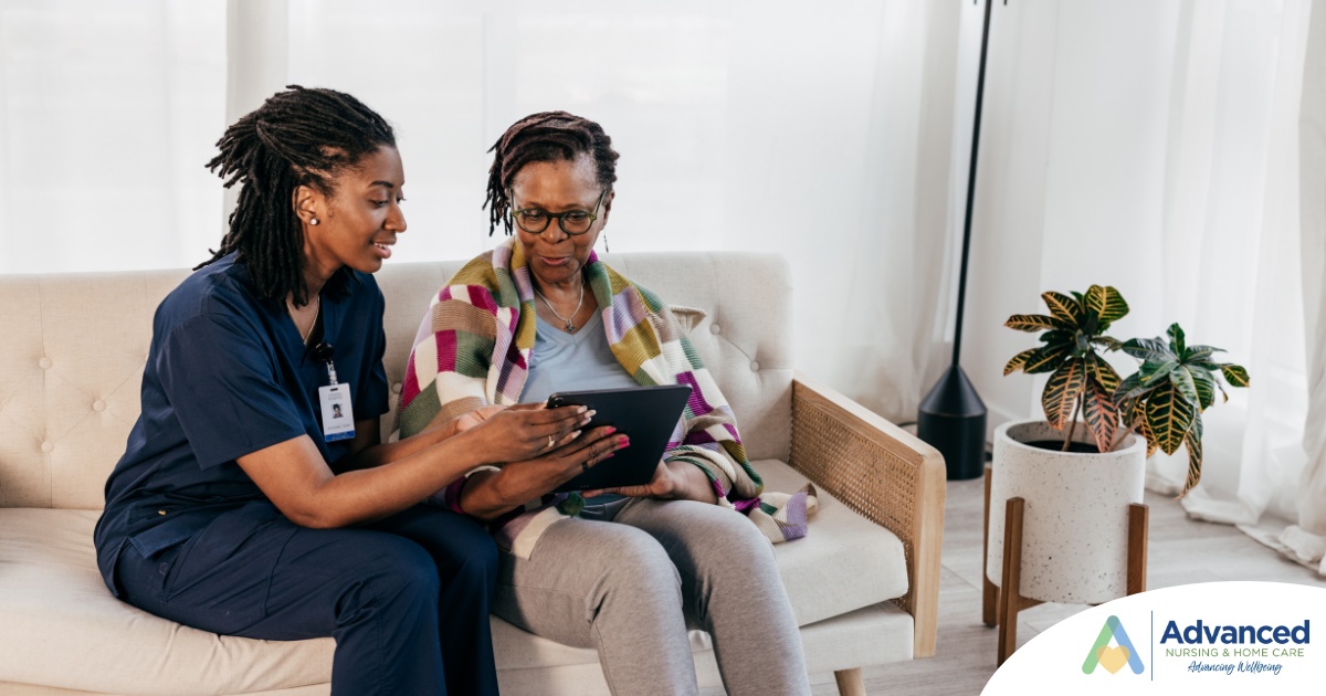 A caregiver talks with a patient while showing her information on a tablet representing the type of thorough communication needed for effective and professional care of home health care patients.