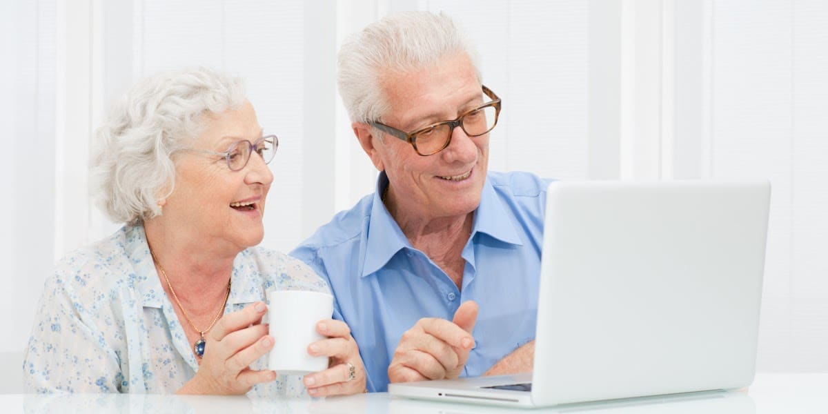 An older couple smiling using a laptop